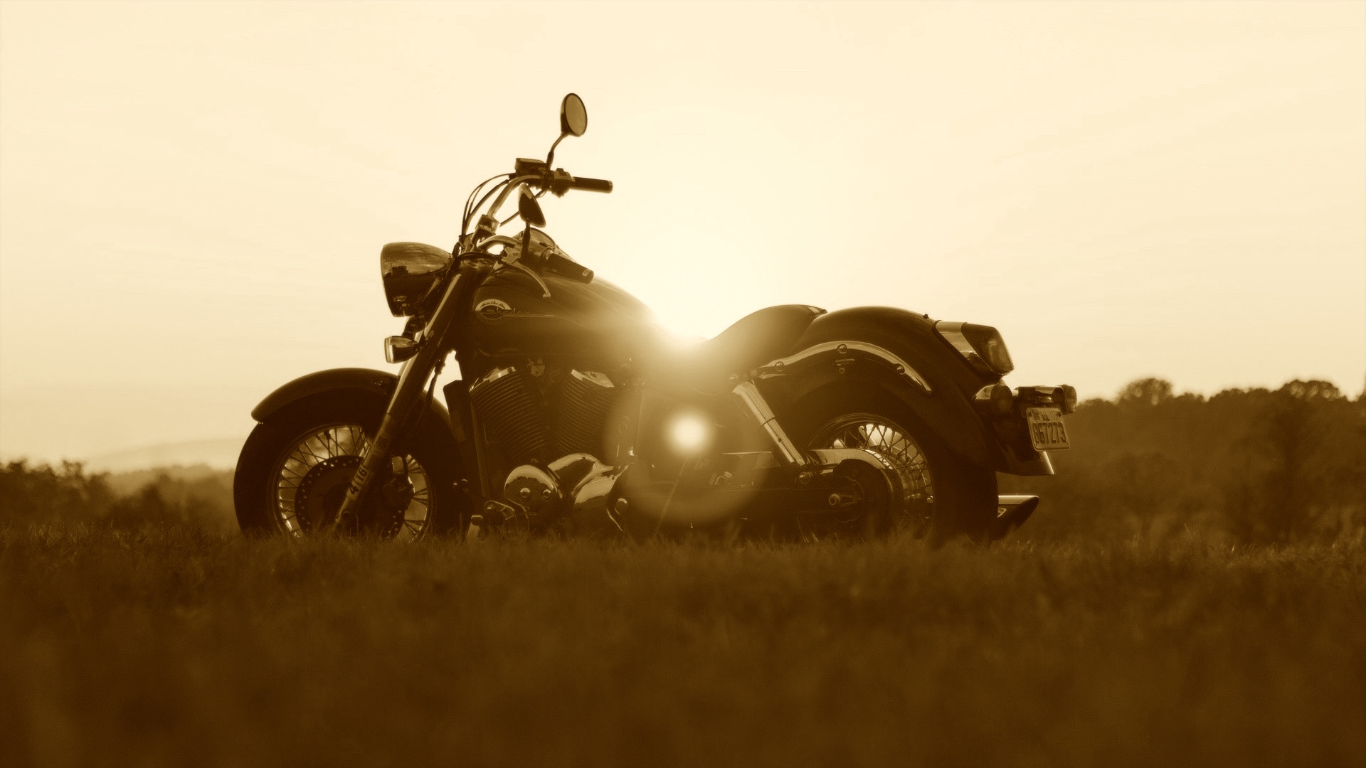 Sepia picture of motorbike in front of sunset.